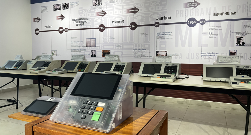 A imagem mostra o Centro de Memória do TRE-CE, com diversas urnas eletrônicas organizadas sobre ...