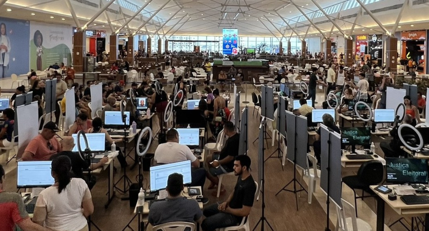 Na foto, em um pátio de shopping, há diversas bancadas de atendimentos do TRE-CE espalhadas pelo...