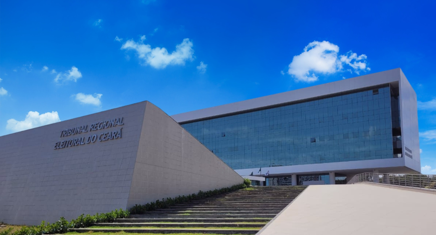 Fotografia da fachada da sede do Tribunal Regional Eleitoral do Ceará. Em primeiro plano, há uma...