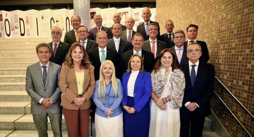 A imagem mostra um grupo de pessoas posando para fotografia em uma escadaria, entre elas, está a...