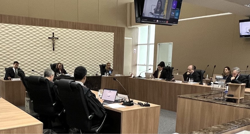 Na foto, há um ângulo lateral do plenário do TRE-CE, com bancada de madeira em formato de "U", t...