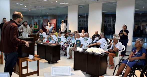 Na primeira foto, um grupo de cerca de trinta pessoas está reunido no Centro de Memória do TRE-C...