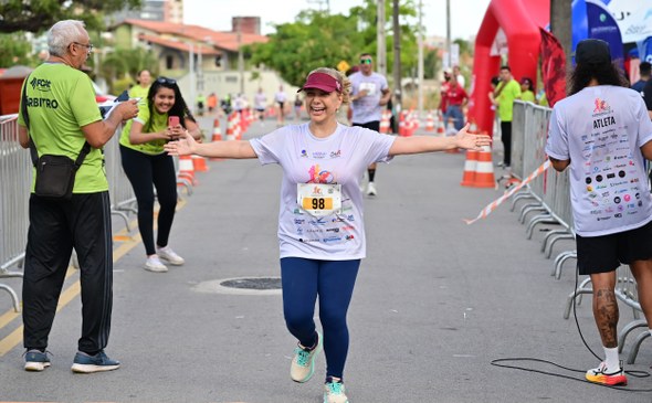 Na segunda imagem, a diretora-geral do TRE-CE se aproxima da linha de chegada. Ela está no centr...