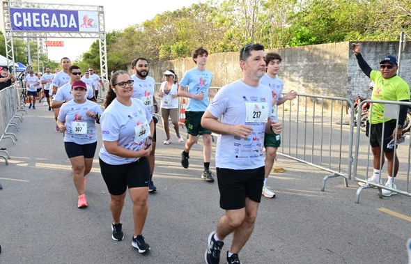 Na sétima imagem, várias pessoas estão cruzando a linha de chegada da corrida. Há uma estrutura ...