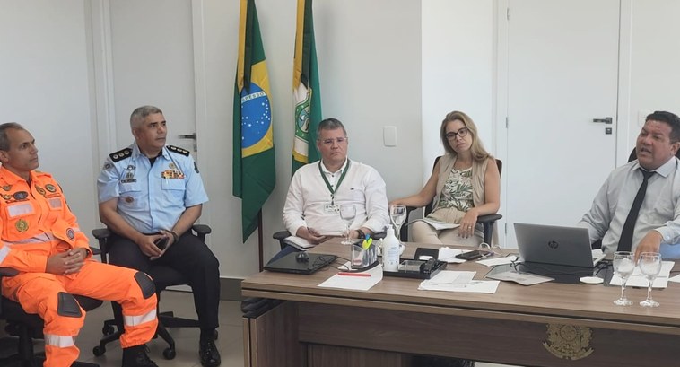 Parceria entre TRE-CE e Corpo de Bombeiros do Ceará busca fortalecer a segurança de unidades da instituição eleitoral Foto em tamanho retangular. Há cinco pessoas na imagem. Todos estão sentados, em um sala de pare...
