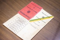 Título aberto e desdobrado, mostrando, a capa dura em vermelho, a primeira página e a página do ...