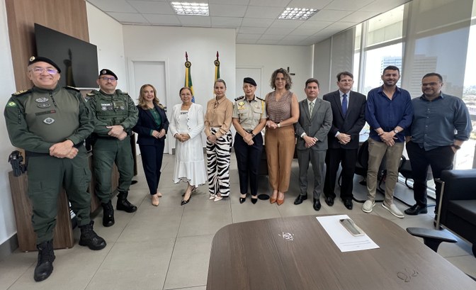 A fotografia mostra um grupo de onze pessoas reunidas em uma sala de reunião, posicionadas lado ...