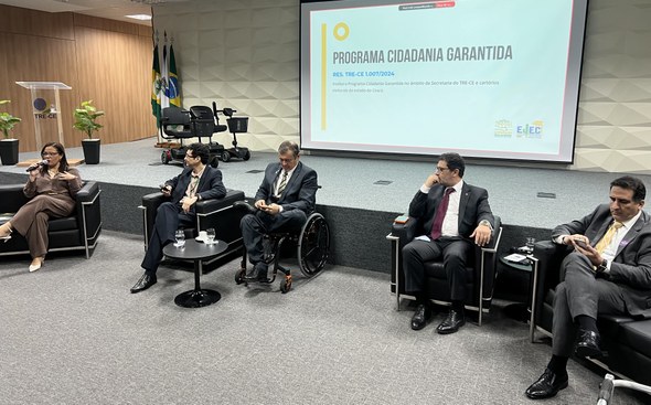 Na primeira foto, no auditório, um grupo de pessoas posa para foto diante de uma tela de projeçã...