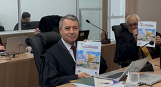 Foto do desembargador Edilberto Oliveira segurando a revista Suffragium. Ao lado dele, o desemba...