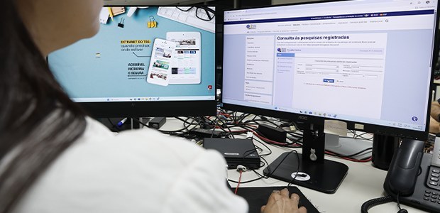 TRE-CE pesquisas eleitorais TSE Foto de pessoa sentada diante de dois monitores, vista de costas. Na tela à esquerda, aparece um...