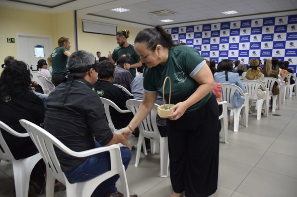 Na imagem, voltando para a sala de treinamento, uma mulher toca a mão de um dos participantes du...