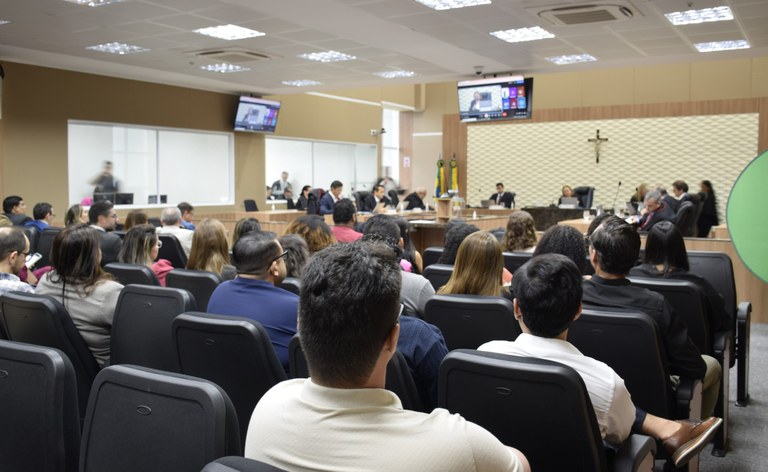 Na imagem, no Pleno do TRE-CE, as fileiras de cadeiras estão ocupadas por pessoas voltadas para ...