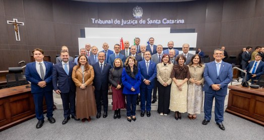 A imagem mostra um grupo de pessoas posicionado para uma fotografia em um ambiente institucional...