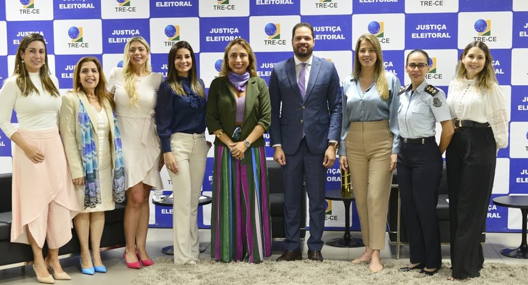 A imagem é um registro fotográfico. Ao fundo, há uma parede estampada por quadrados brancos e az...