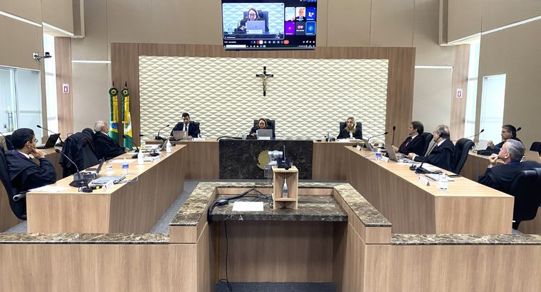 A imagem mostra uma sala de sessões de TRE-CE. No centro, há uma mesa principal em formato de U....