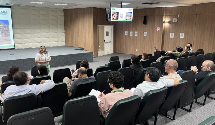 Na primeira imagem, há o auditório do TRE-CE com fileiras de cadeiras ocupadas por pessoas senta...