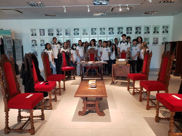 Registro fotográfico feito no Centro de Memória. Nele, há cadeiras acolchoadas em tecido vermelh...