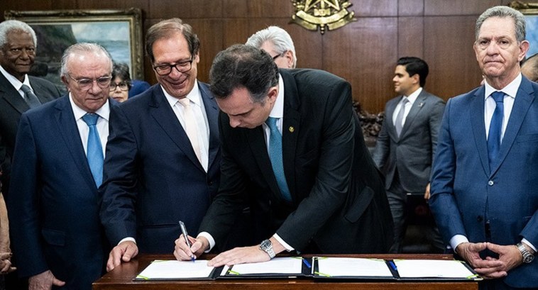 Comissão de juristas recebe sugestões para atualização do Código Civil A imagem é um registro fotográfico. Nele, há alguns homens de terno atrás de uma mesa de madeira...