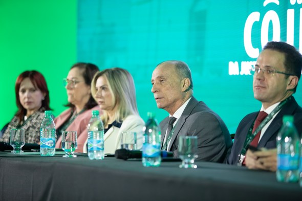 Comitiva do TRE-CE participa de Encontro Nacional do Colégio de Ouvidores da Justiça Eleitoral Na segunda foto, seis pessoas estão sentadas lado a lado atrás da mesa de honra do evento. Uma d...