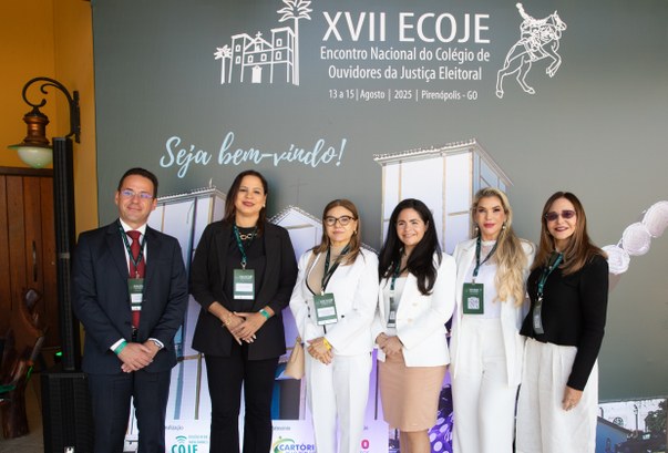 Comitiva do TRE-CE participa de Encontro Nacional do Colégio de Ouvidores da Justiça Eleitoral Na primeira foto, seis pessoas posam em pé para a câmera, sorrindo, em frente a um painel que id...