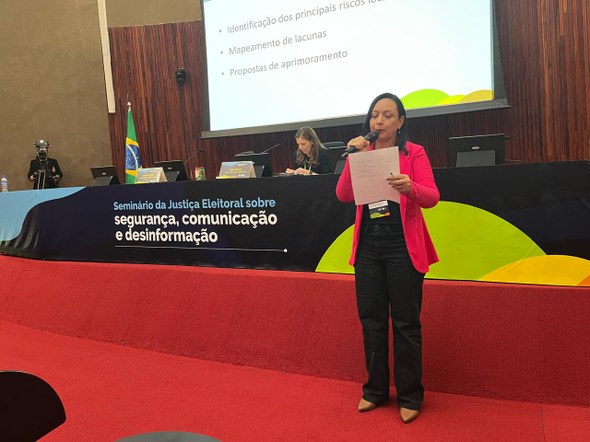 Comitiva do TRE-CE participa de seminário nacional em preparação às Eleições 2026 Na imagem, a assistente da Unidade Militar do TRE-CE aparece falando ao microfone e segurando um...