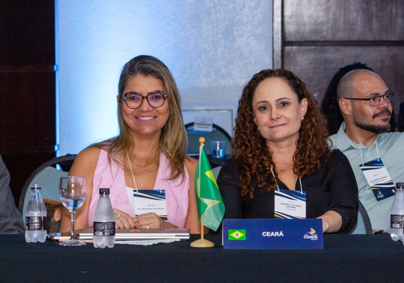 Na foto, duas juízas do TRE-CE posam lado a lado. Uma usa rosa e outra usa preto. Elas estão sen...