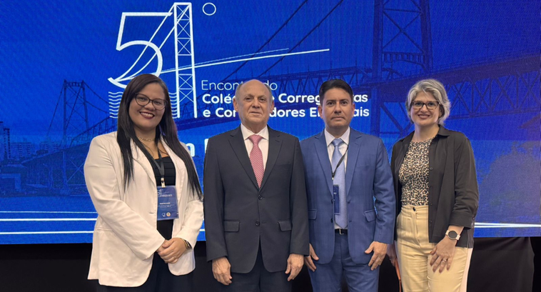 CRE-CE participa do 54ª Encontro do Colégio de Corregedoras(es) Eleitorais A imagem mostra quatro pessoas posando em frente a um painel azul com o texto “54º Encontro do C...