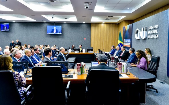 A imagem mostra uma sala de reuniões do Conselho Nacional de Justiça (CNJ). À direita, há uma lo...