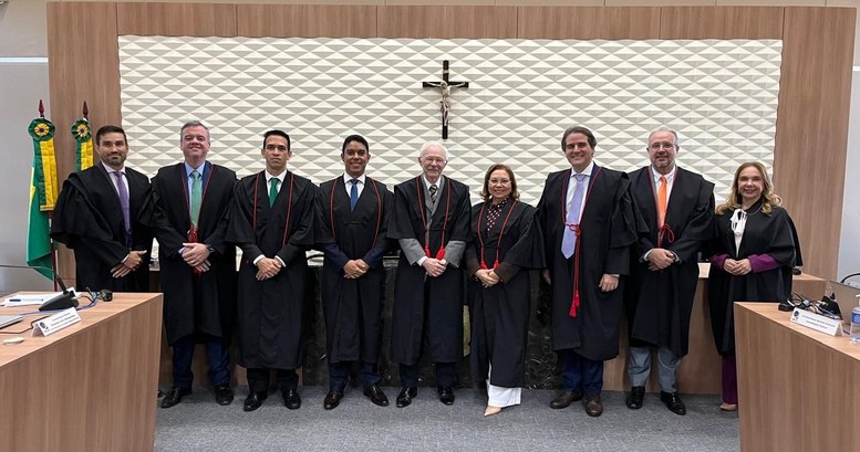A imagem mostra um grupo de pessoas em pé, lado a lado, no Pleno do TRE-CE. Todas estão voltadas...