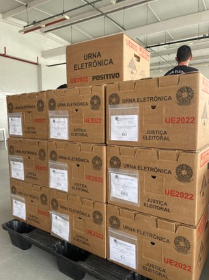 Registro fotográfico feito na sede do TRE-CE. Nele, há uma pilha de caixas de papelão, que trans...