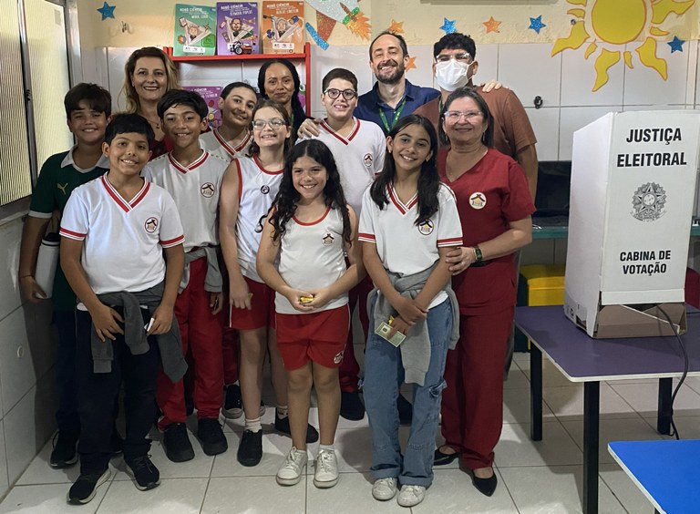 Na imagem, há um grupo de crianças e adolescentes, meninos e meninas, acompanhados por adultos, ...