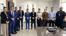A imagem mostra um grupo de dez pessoas em uma sala de reuniões, posicionadas lado a lado e volt...