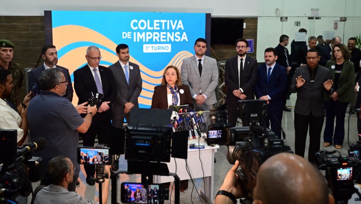 Na imagem, a presidente do TRE Ceará concede uma entrevista coletiva posicionada ao centro, atrá...
