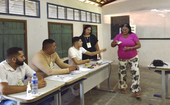 IMG_2709.JPG A imagem registra outro momento de atendimento em uma seção eleitoral. Uma eleitora entrega seu ...