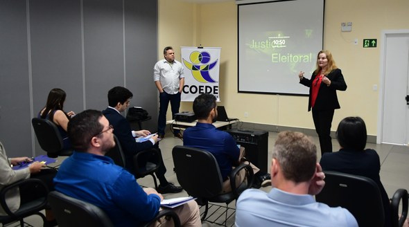 Na primeira foto, os novos servidores estão sentados em cadeiras de escritório, enquanto assiste...