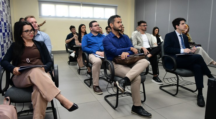 Na primeira foto, os novos servidores estão sentados em cadeiras de escritório, enquanto assiste...