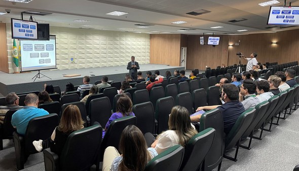 Na primeira foto, os novos servidores estão sentados em cadeiras de escritório, enquanto assiste...