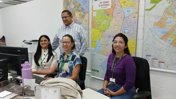 Na primeira foto, os novos servidores estão sentados em cadeiras de escritório, enquanto assiste...