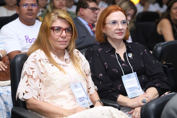 Ouvidoria da Mulher do TRE-CE participa do II Encontro Nacional PopRuaJud, no Maranhão Duas mulheres estão sentadas em um auditório com outras pessoas também sentadas. Elas usam crach...