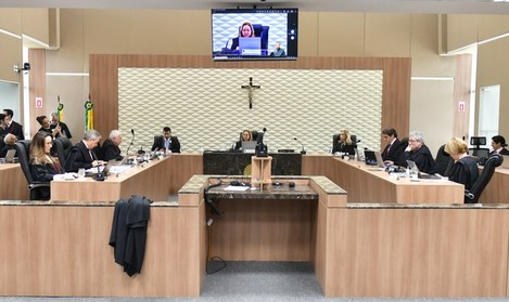 A imagem mostra o Plenário do TRE-CE durante uma sessão presencial e por videoconferência. A sal...