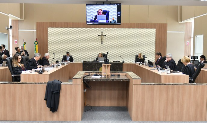 A imagem mostra o Plenário do TRE-CE durante uma sessão presencial e por videoconferência. A sal...