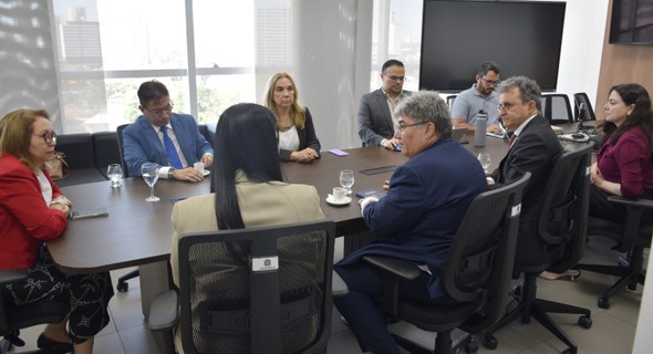 Presidência do TRE-CE recebe visita institucional dos dirigentes da OAB-CE A imagem mostra o mesmo espaço em outro ângulo, agora com nove pessoas sentadas ao redor da mesa...