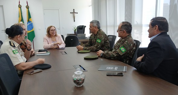 Presidente do TRE-CE recebe visita de general que se despede do comando da 10ª Região Militar Na foto, o grupo aparece reunido ao redor de uma mesa de reuniões no mesmo ambiente.