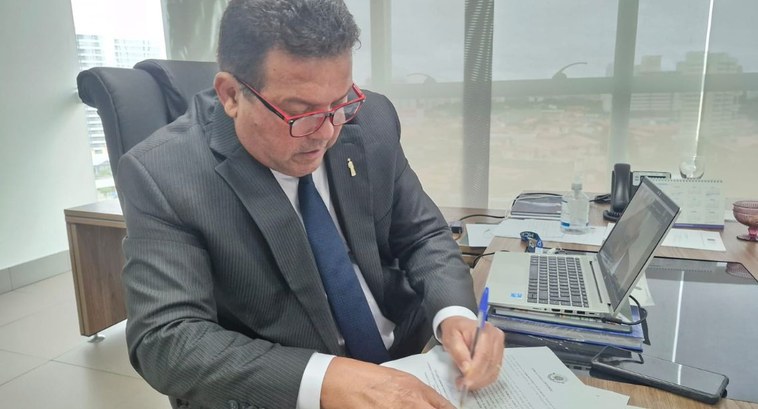 Presidente do TRE-CE toma posse vice-presidente do Coptrel Foto em formato retangular. O presidente do TRE-CE está assinando um documento. Está vestido com...