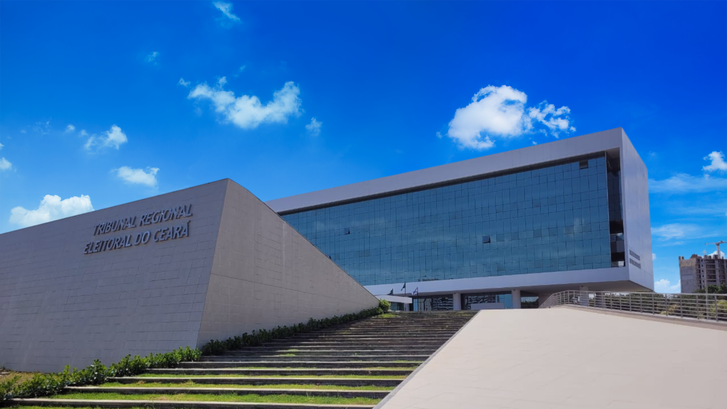 Fotografia da fachada da sede do Tribunal Regional Eleitoral do Ceará. Em primeiro plano, há uma...
