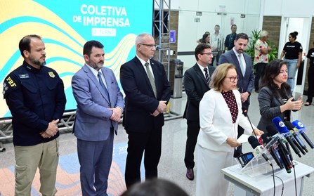 Na imagem, em plano médio, a presidente do TRE-CE segura papéis, enquanto fala em microfones de ...
