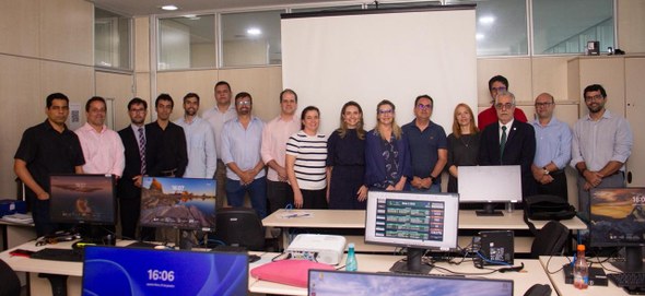 Na imagem, no mesmo espaço, dezessete pessoas posam para a foto. O ambiente conta com várias mes...