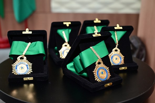 TRE-CE agracia cinco personalidades com Comenda de Mérito ao Ouvidor durante sessão solene Os registros fotográficos foram feitos no plenário do TRE-CE. Ao centro da parede, há um crucifi...