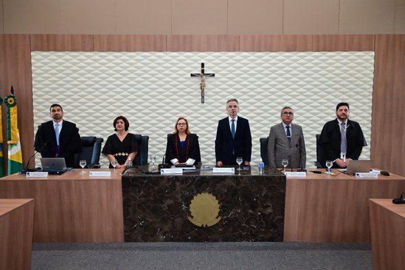 TRE-CE agracia cinco personalidades com Comenda de Mérito ao Ouvidor durante sessão solene Os registros fotográficos foram feitos no plenário do TRE-CE. Ao centro da parede, há um crucifi...