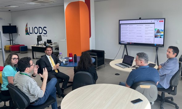 TRE-CE ampliará campanhas de incentivo à participação de pessoas com deficiência nas eleições Na primeira imagem, oito pessoas estão sentadas ao redor de uma mesa de reuniões, sendo cinco de...